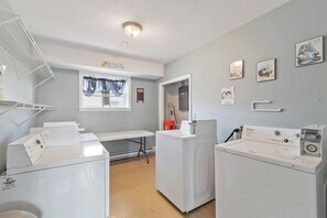 A laundry room with a washing machine, dryer, and a shelf with folded clothes.