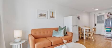 Ein modernes Wohnzimmer mit einer Couch, einem kleinen Tisch und einem Essbereich mit Stühlen.