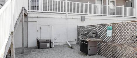 A fenced outdoor area with a grill and a water heater.
