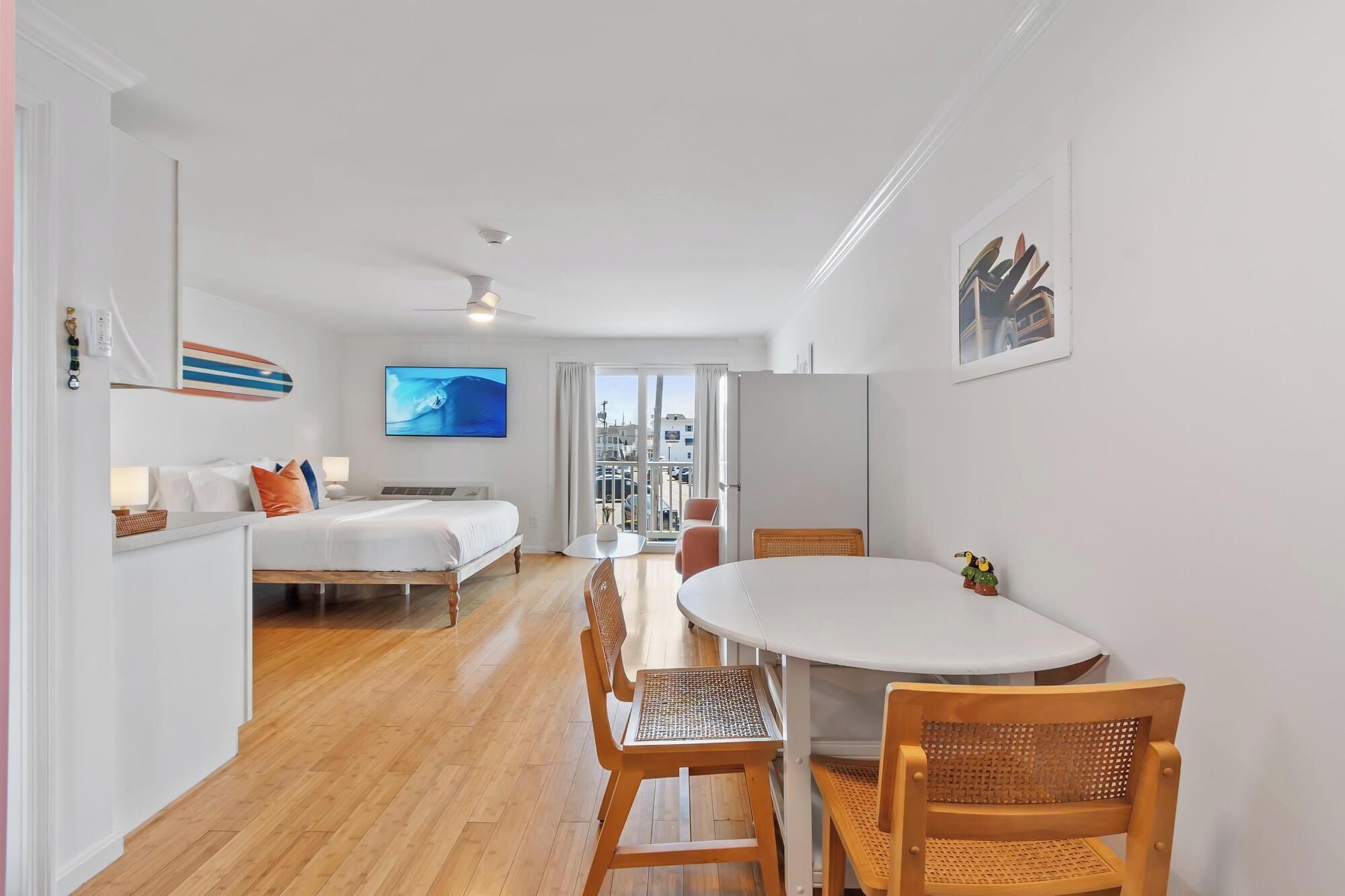 Una habitación de hotel moderna con una cama, una mesa de comedor con sillas, un televisor y vista a la ciudad.