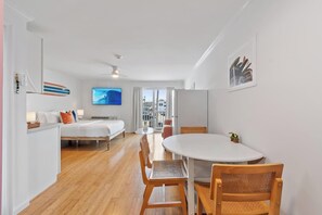 Una moderna camera d'albergo con un letto, un tavolo da pranzo con sedie, una TV e vista sulla città.
