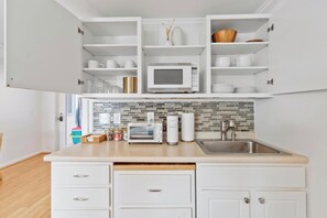 A kitchen with white cabinets, a microwave, a toaster, and a sink.