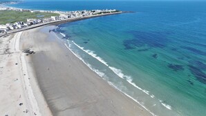 Vista aérea de una zona costera con playa, paseo marítimo y edificios a lo largo de la orilla.