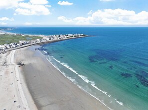 Una vista aerea di una zona costiera con una spiaggia, un lungomare e edifici lungo la riva.