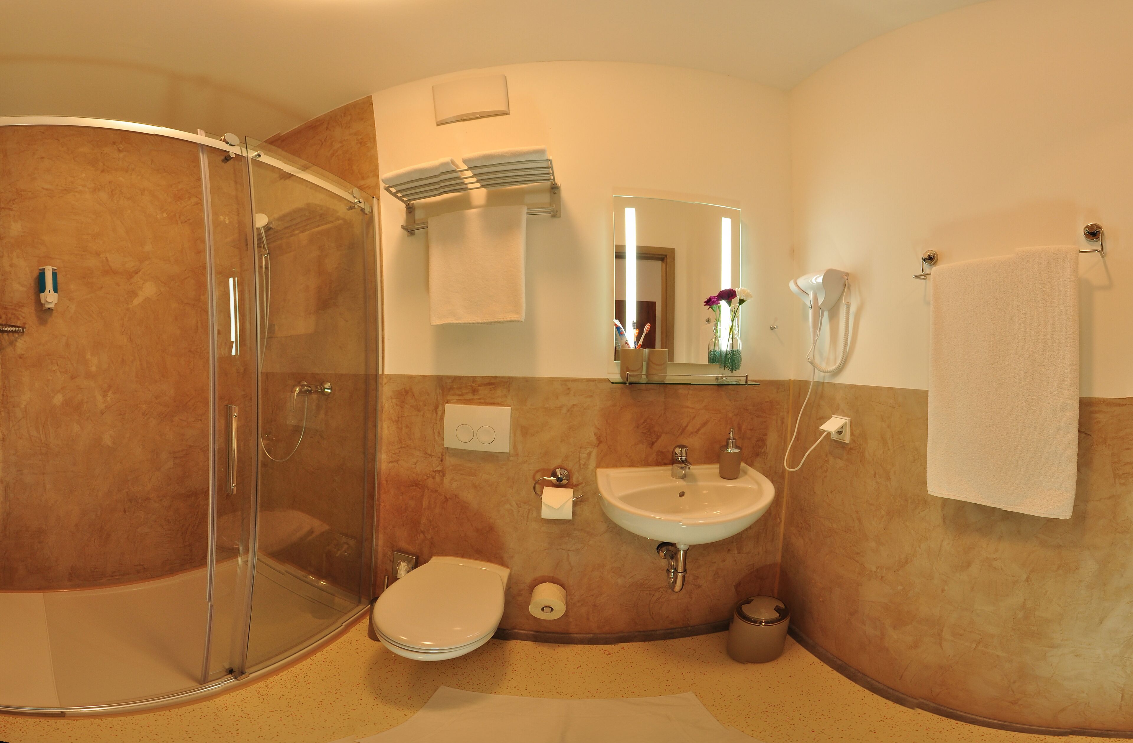 A bathroom with a glass-enclosed shower, a sink, a toilet, and a mirror.
