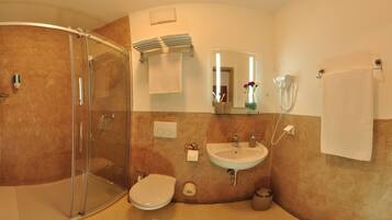 A bathroom with a glass-enclosed shower, a sink, a toilet, and a mirror.