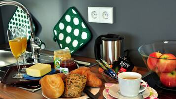 A breakfast setup with croissants, bread, butter, jam, coffee, and apples.