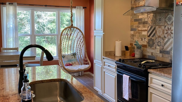 Une cuisine dotée d’un plan de travail en granit, d’un évier en acier inoxydable et d’une chaise suspendue.