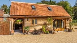 Une maison en bois avec un toit en tuiles, une véranda en bois et des plantes en pot.