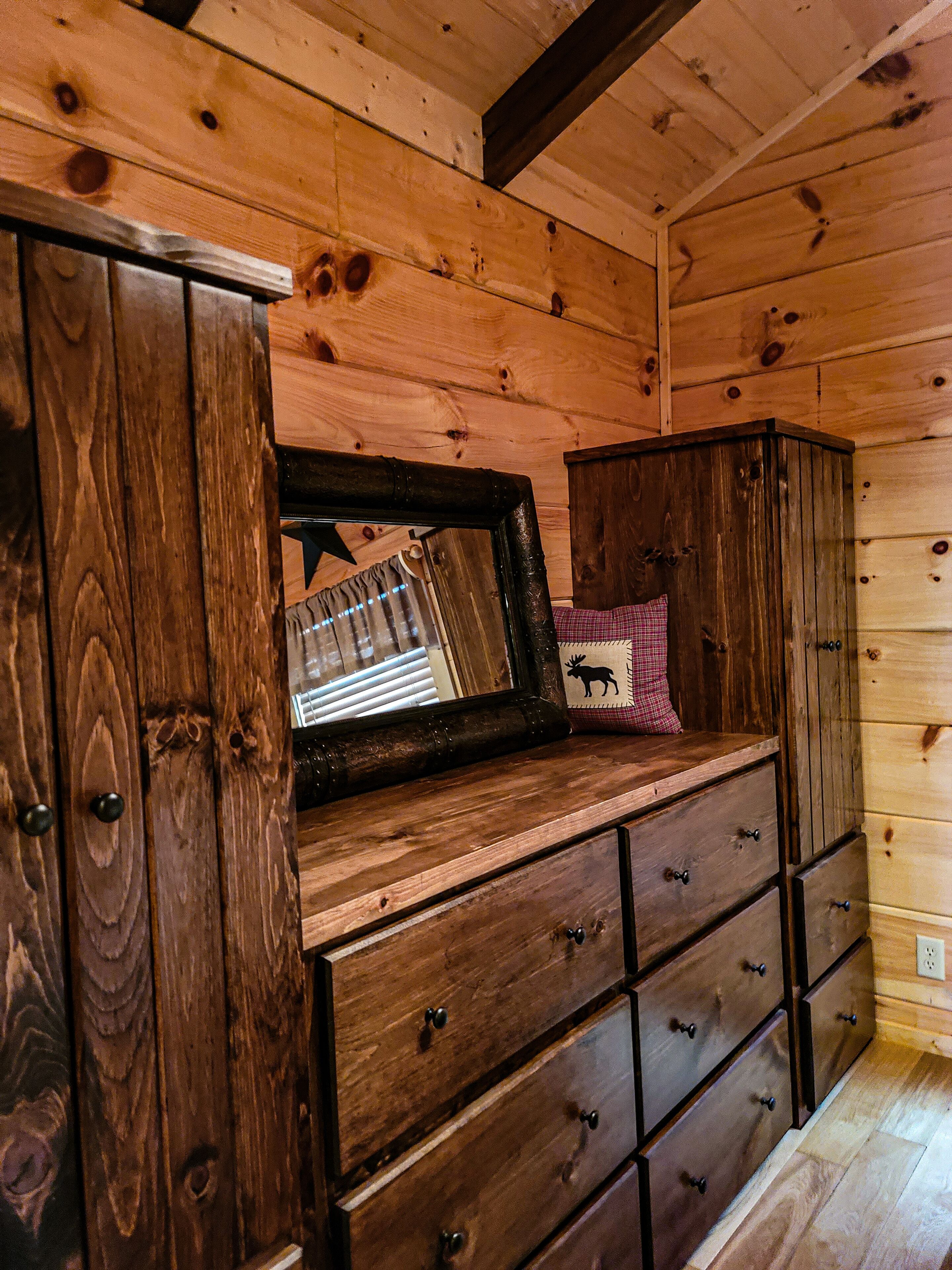 A wooden dresser with multiple drawers and a mirror.