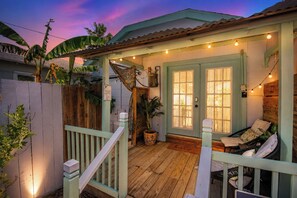 Eine Holzterrasse mit Lichterketten, eine Tür mit Fenster und eine Bank.