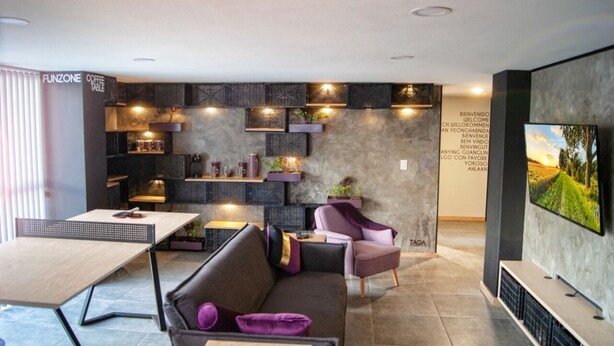 A modern interior with a sofa, a table, and a TV. There are shelves with decorative items and a wall with a welcome message. - Perfect location (Del Valle Norte)