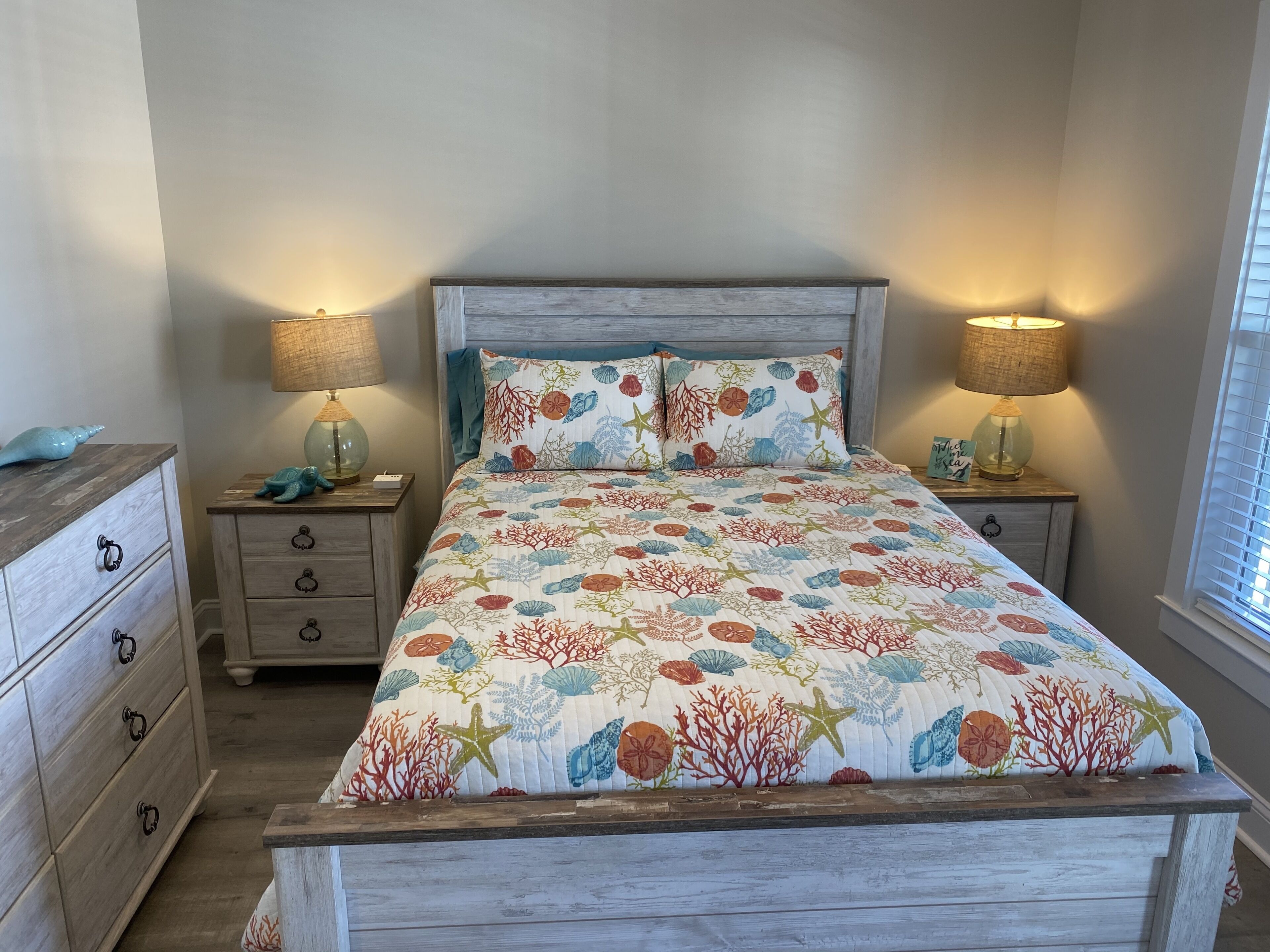 A bedroom with a bed, two nightstands, a dresser, and lamps.