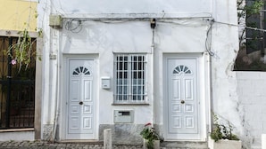 A white building with two symmetrical doors, a small window with a grid pattern, and a mailbox. - A43 - Castle Arch Apartment (Lagos)