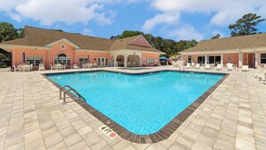 A swimming pool with a 4ft no-entry zone, surrounded by lounge chairs and a building with a red roof.