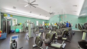 A gym with exercise equipment, a ceiling fan, and a teal wall.