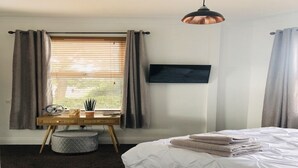A bedroom with a bed, a desk with a chair, a television, and a window with curtains. - Modern 1-Bed Apartment in Chapel Allerton – Great for Longer Stays & Remote Work (Chapel Allerton)