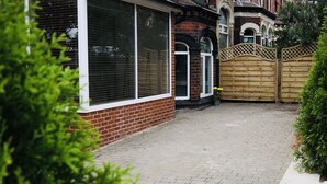 A brick house with a paved driveway, a wooden gate, and a small garden area. - Modern 1-Bed Apartment in Chapel Allerton – Great for Longer Stays & Remote Work (Chapel Allerton)