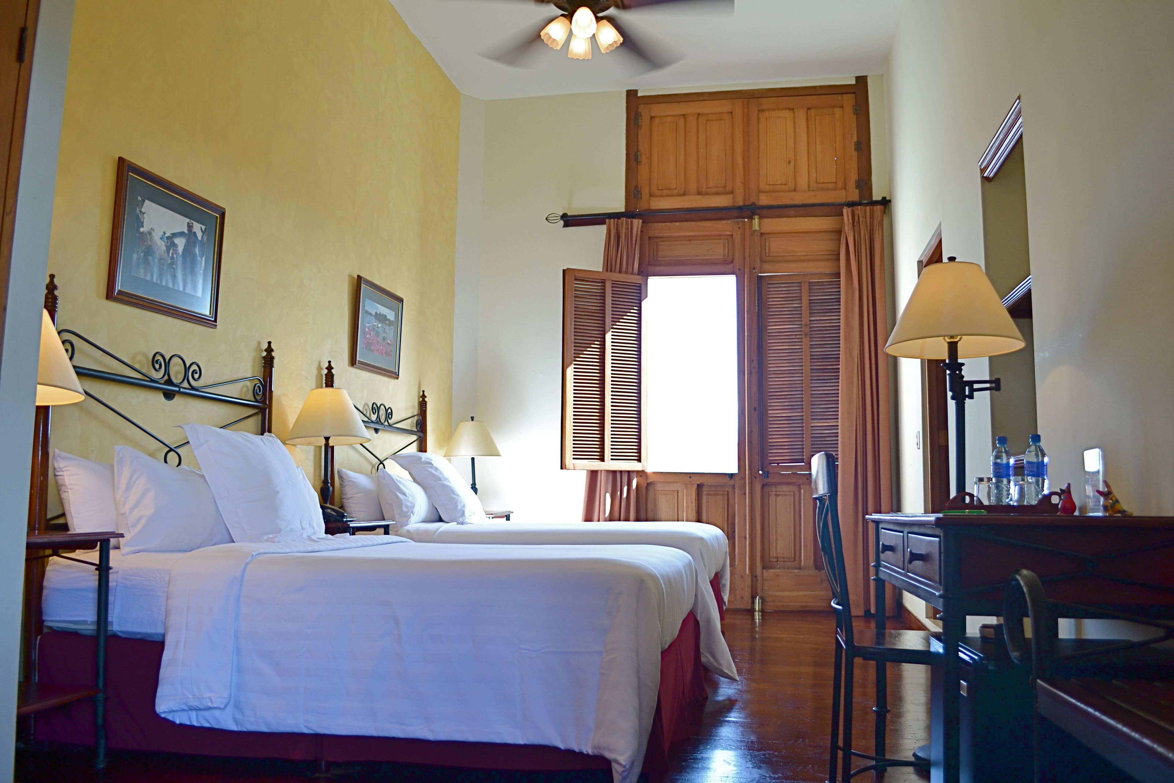A hotel room with two beds, a desk, and a chair.