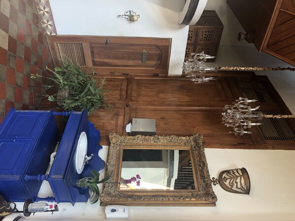 A bathroom with a blue sink, a mirror, a potted plant, and a wooden door. - Hotel Dario (Granada)