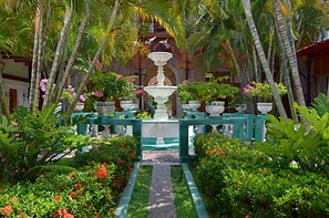 A garden with a central fountain, surrounded by potted plants and a pathway. - Hotel Dario (Granada)