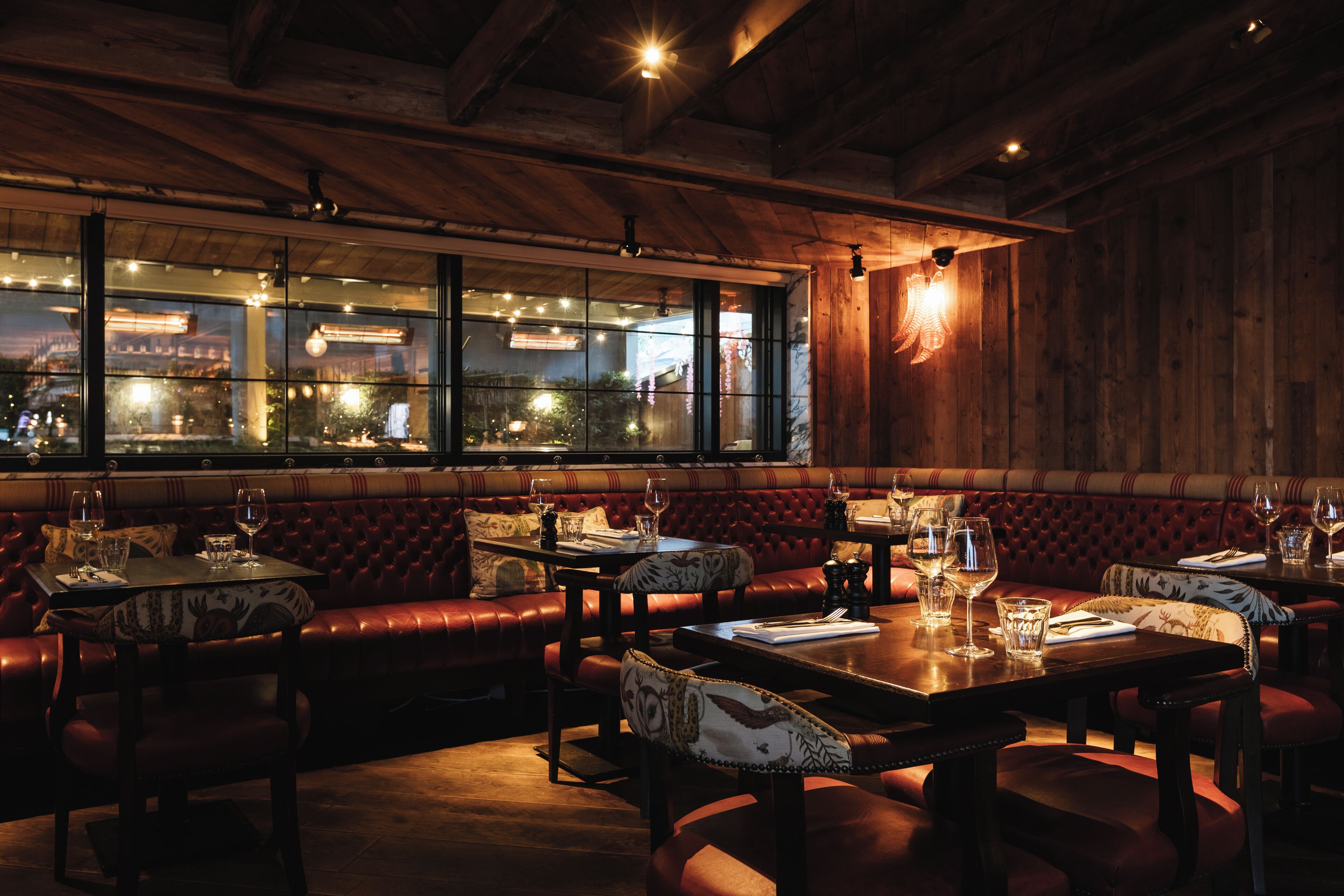 Ein Restaurant mit Holzeinrichtung, Ledersitzbänken und gedeckten Tischen.