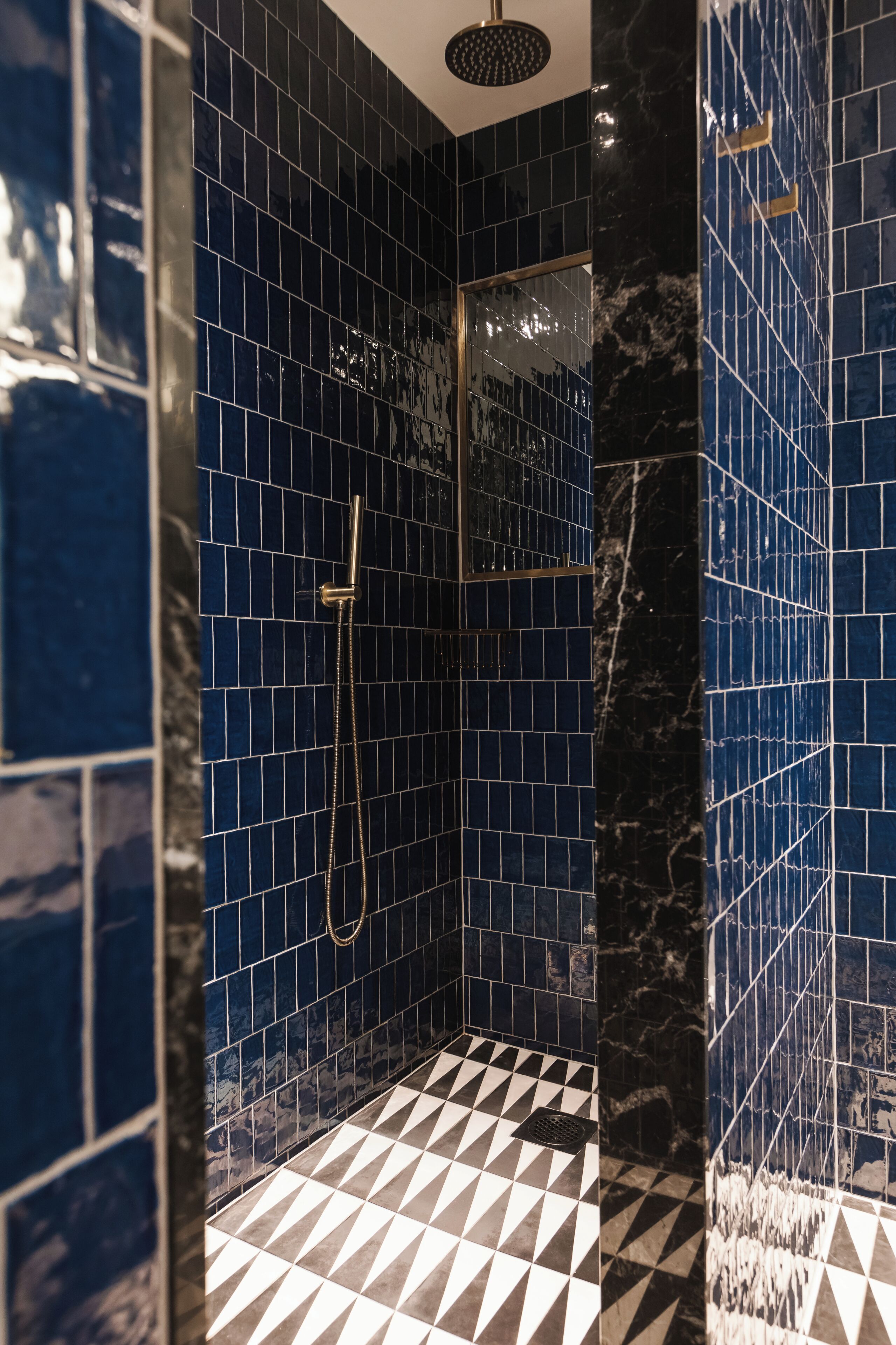 A bathroom with blue tiled walls and a black and white checkered floor.