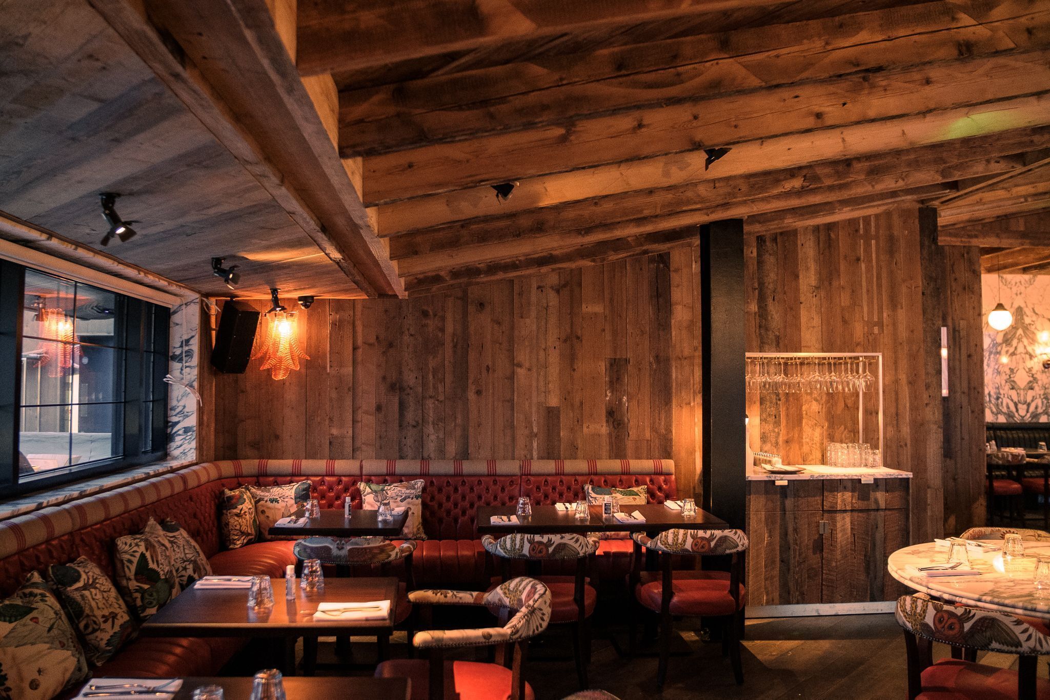 Ein gemütliches Restaurant mit Holzwänden, einer Bar und Sitzgelegenheiten, darunter Boxsitzgruppen und Tische.