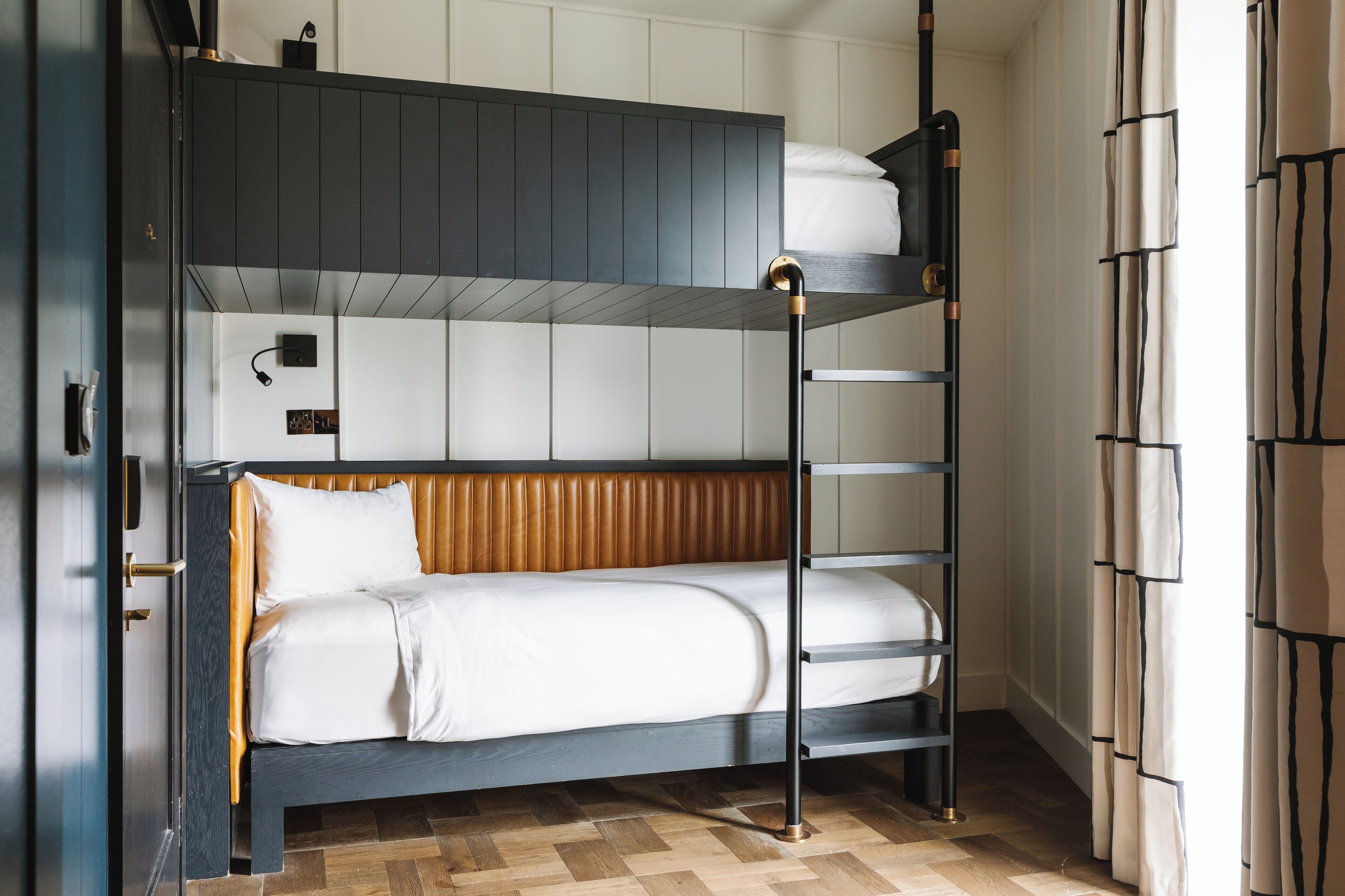 A bunk bed with a wooden headboard, a bedside table, and a floor lamp.