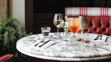 A round marble table with a red upholstered bench, a small potted plant, and a wall-mounted light fixture.