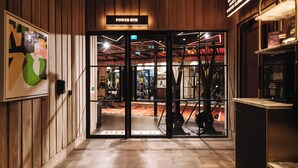 A gym entrance with wooden paneling, a sign reading "POWER GYM," and exercise equipment visible through the glass doors. - The Dean Cork (Cork)