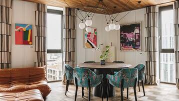 A dining area with a round table, four chairs, and a brown sofa.