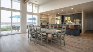 A modern kitchen with a dining area, large windows, and a view of the outdoors. - The Oasis at Canyon Lake - Gorgeous & Modern Waterfront Home + Pool + Sweeping Lake Views (Canyon Lake)