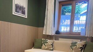Een woonkamer met een bank, een getextureerd vloerkleed, een houten salontafel en een lijst met een foto aan de muur.