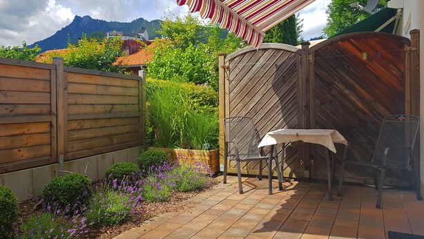 Een terras met een tafel en stoelen, een houten omheining en uitzicht op bergen.