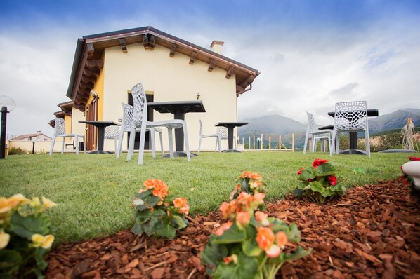 A building with outdoor seating, a grassy area, and a mountain view. - Albergo Diffuso Amatrice (Amatrice)