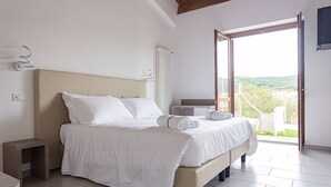 A bedroom with a bed, bedside tables, a radiator, and a view of the outdoors. - Albergo Diffuso Amatrice (Amatrice)