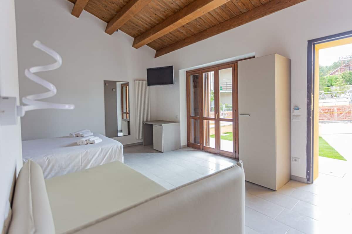 A bedroom with a bed, a desk, a wardrobe, and a television.
