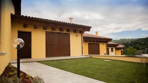 A two-story building with a yellow facade, large wooden doors, and a tiled roof. - Albergo Diffuso Amatrice (Amatrice)
