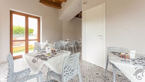 A dining area with a large table and chairs, a wooden ceiling, and a view through a glass door. - Albergo Diffuso Amatrice (Amatrice)
