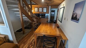 Ein Essbereich mit Holztisch und -stühlen, einer Treppe und einer Küche im Hintergrund.