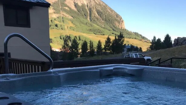 Ein Whirlpool mit Bergblick, ein Gebäude mit Schrägdach und ein geparktes Fahrzeug.
