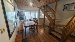 Ein Innenraum mit Holzboden, Essbereich, Treppe und Kamin.