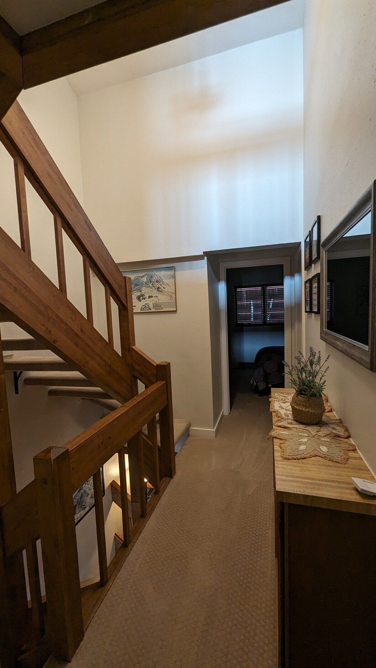 A staircase leading to a second floor, a framed picture on the wall, and a small table with a plant.