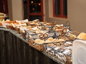 A buffet counter with various breads and pastries displayed in baskets. - Ana Maria Apart Hotel (Arcos)