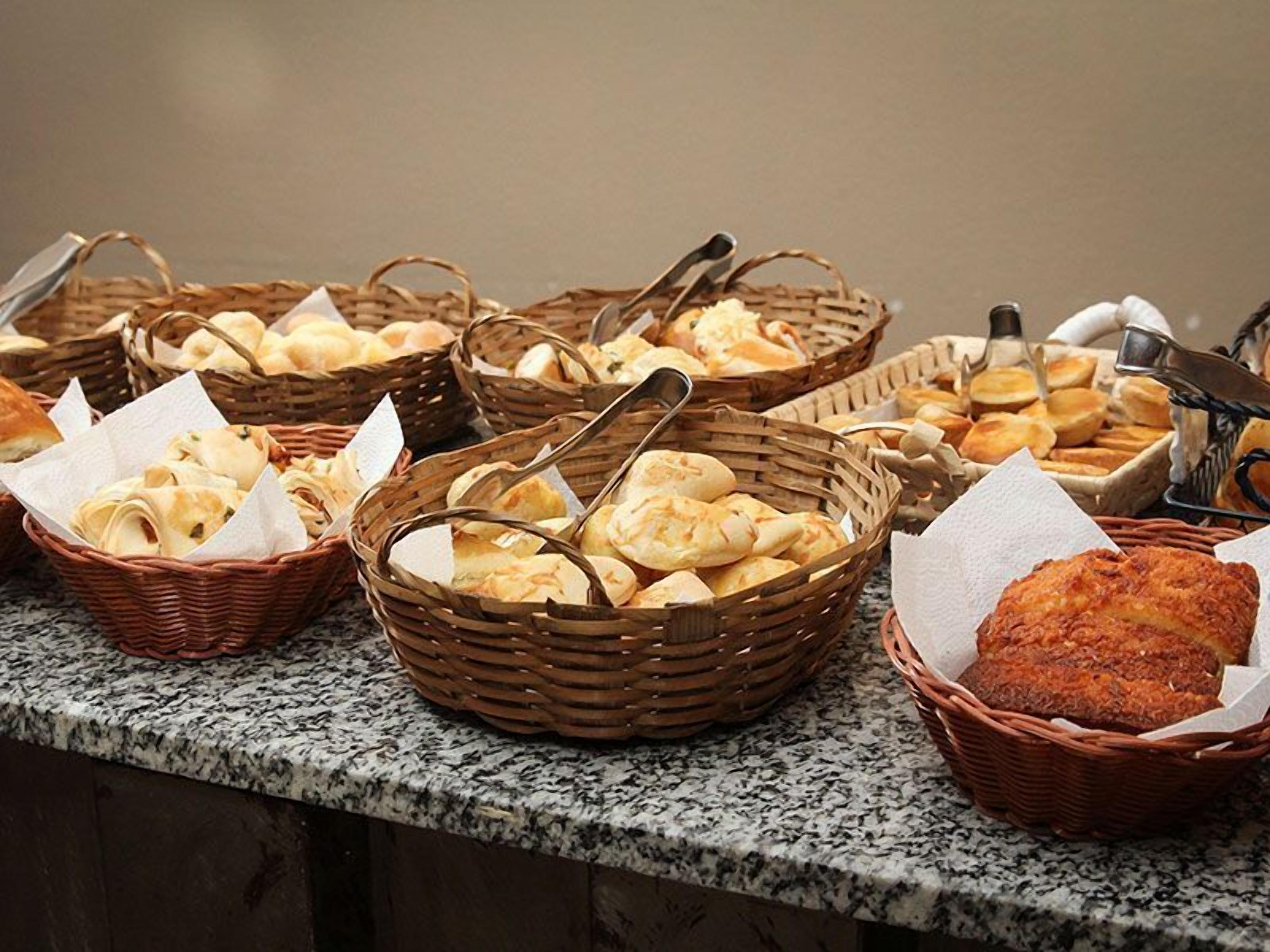 A buffet table with various breads and pastries in wicker baskets.