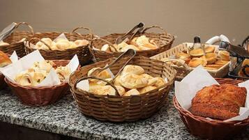 A buffet table with various breads and pastries in wicker baskets.