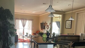 A modern kitchen with a central island, pendant lighting, and a dining area with a red rug. - Lake house - unit 309 (Willis)