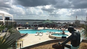 A pool area with lounge chairs, a hot tub, and a view of the water. - Lake house - unit 309 (Willis)
