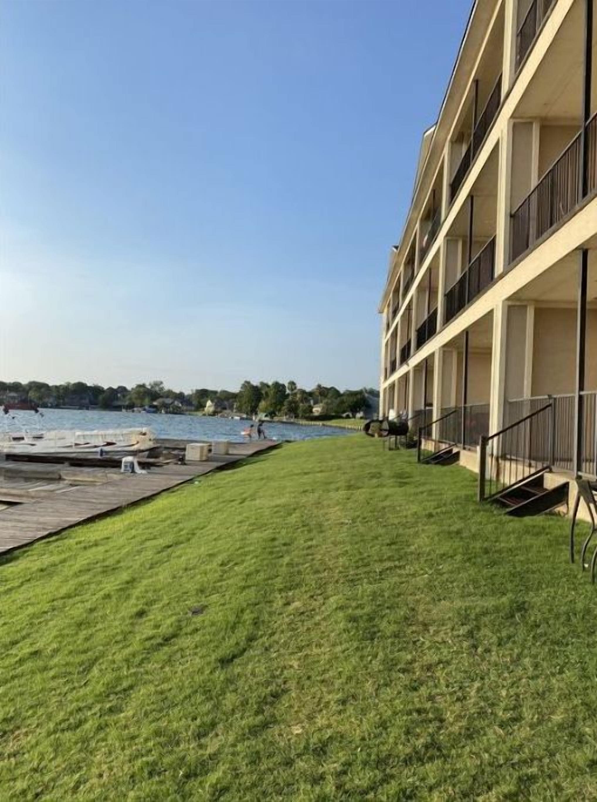 A building with a grassy lawn and a dock extending into a body of water.